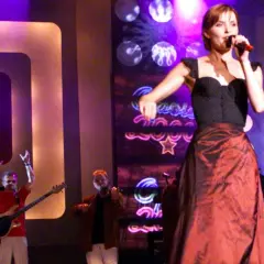 Wokalistka śpiewa na scenie, a zespół gra. Koncert w maju w tramwaju, pełen energii i światła.