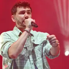 Kamil Bednarek śpiewa na scenie, w blasku reflektorów. Jego muzyka porywa tłumy.