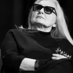 Magda Umer w okularach, z długimi blond włosami, siedzi z rękami skrzyżowanymi na piersi. Jej piosenki magdy umer alfabetycznie mogłyby być tematem tej rozmowy.