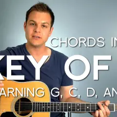 Mężczyzna z gitarą uczy akordów w tonacji G. Chwała na wysokości chwyty!