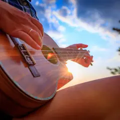 Słońce zachodzi, a ja gram na ukulele. Ciepłe promienie oświetlają moje dłonie i drewniany instrument.