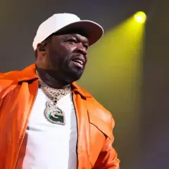 50 Cent w pomarańczowej kurtce i białej czapce, z naszyjnikiem z literą G. Czy to jego 21 pytań do fanów?