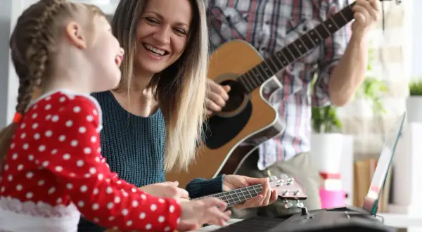 Rodzina gra na instrumentach, tworząc piosenki o mamie. Radość i muzyka wypełniają dom.