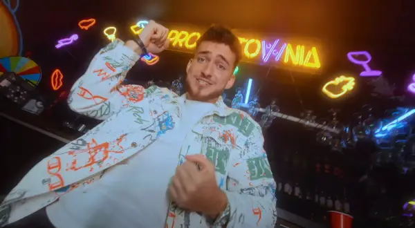 Hej, co zrobiłaś? Jaka głupia byłaś! Młody mężczyzna w kolorowej kurtce tańczy na tle neonów i baru.