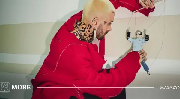 Quebonafide w czerwonym swetrze steruje marionetką, jakby tworzył swoje utwory.