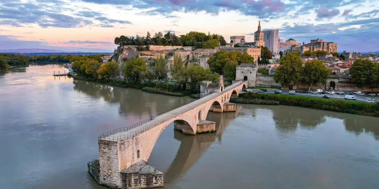Słynny Pont d'Avignon, znany też jako Pont Saint-Bénézet, rozciąga się nad rzeką Rodan. W tle widać zabytkowe budowle miasta.
